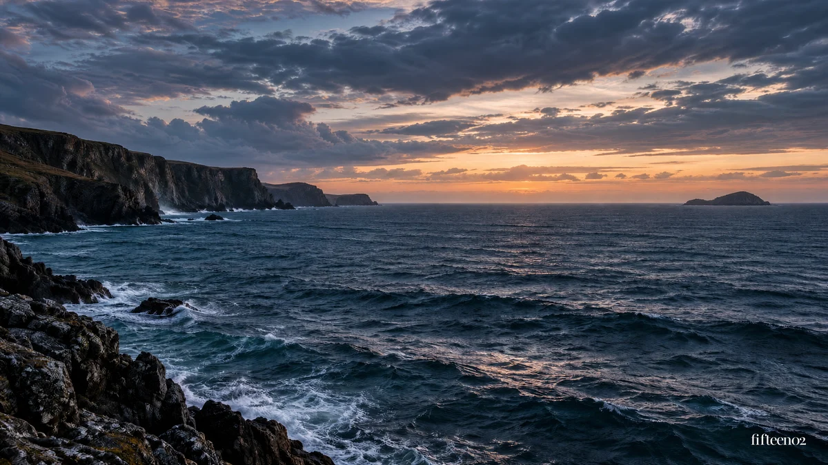 A rocky coastline and dark blue sea beneath a sunset, with a small fifteen02 wordmark.